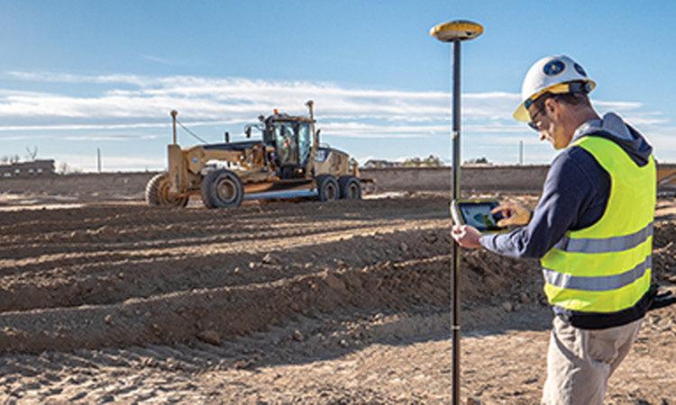 Site Control Surveyor with Moto Grader In Background on Jobsite